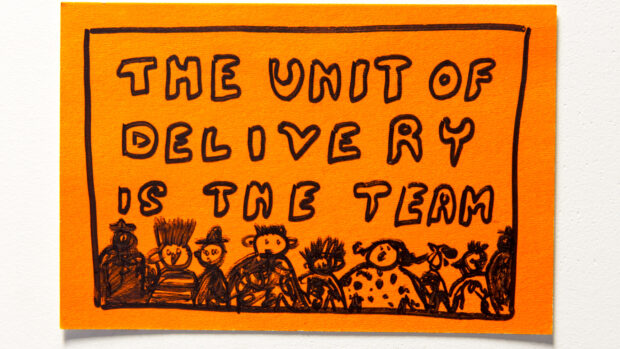 Post-it note with a drawing of people and text that reads "The unit of delivery is the team"