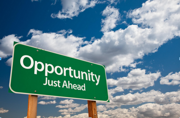 Sign reading 'Opportunity just ahead' against background of blue sky with clouds