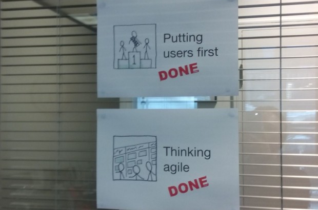 Two A4 papers hanging on the window with drawings and text that reads "Putting users first" and "Thinking agile". Both sheets of paper are stamped as "Done"