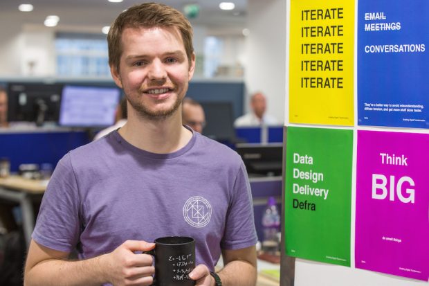 Thomas Fast Streamer in DEFRA. The posters behind him say: "Iterate", "No email meetings, instead conversations", "Think Big", "Data, Design, Delivery at Defra". 