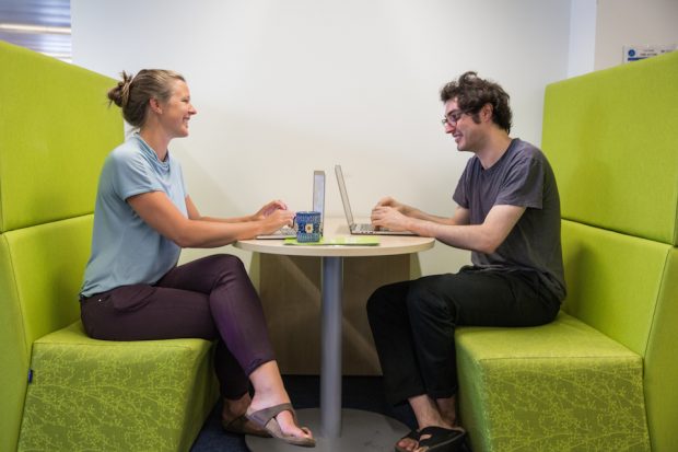 Jo Lee, Data Scientist, talking to a colleague and working on the laptop