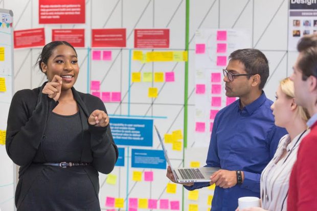 Digital, Data and technology apprentices talking to each other next to the post-it notes wall