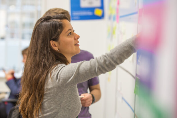 Colleagues are posting the post-it notes on the white board 