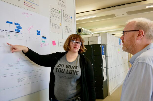 Liz Lutgendorff talking to a colleague next to a project board