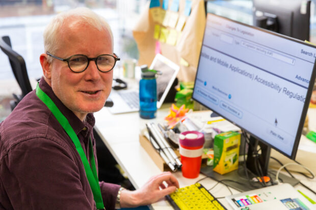 Kevin McLaughlin sitting at the computer screen and smiling at the camera