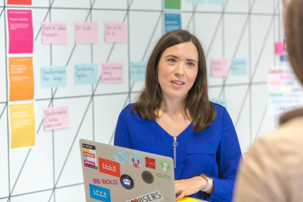 Helen Morris, talking to a colleague and holding the laptop