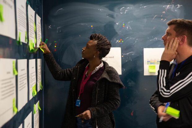 Colleagues putting post-it notes on a wall