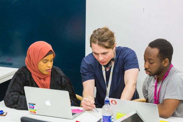 Three people working together on laptops.