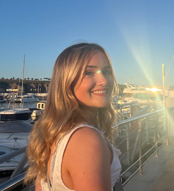 Photograph of Abigail with blue sky and boats behind her